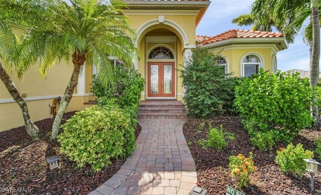 doorway to property with a tile roof, french doors, and stucco siding