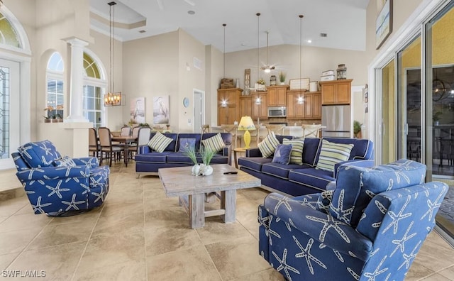 living room with high vaulted ceiling, decorative columns, and a notable chandelier