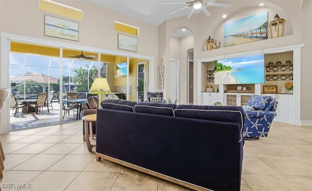 living room featuring ceiling fan, light tile patterned floors, and a towering ceiling