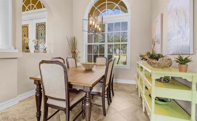 tiled dining area with a notable chandelier, arched walkways, and baseboards