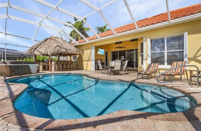 outdoor pool featuring a ceiling fan, glass enclosure, a patio, and outdoor dry bar