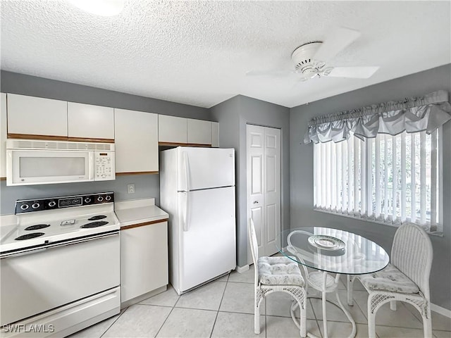 kitchen featuring light tile patterned floors, a textured ceiling, white appliances, a ceiling fan, and light countertops