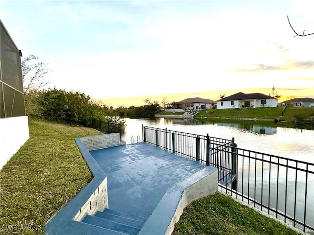 exterior space with a water view, fence, and a lawn