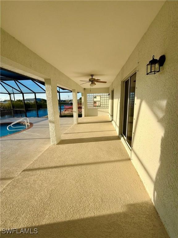 view of patio featuring a ceiling fan, a lanai, and a water view