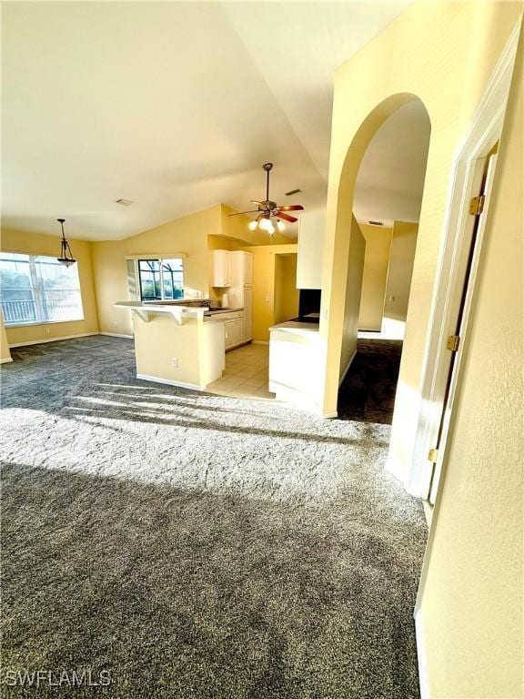 kitchen with light carpet, open floor plan, arched walkways, and vaulted ceiling