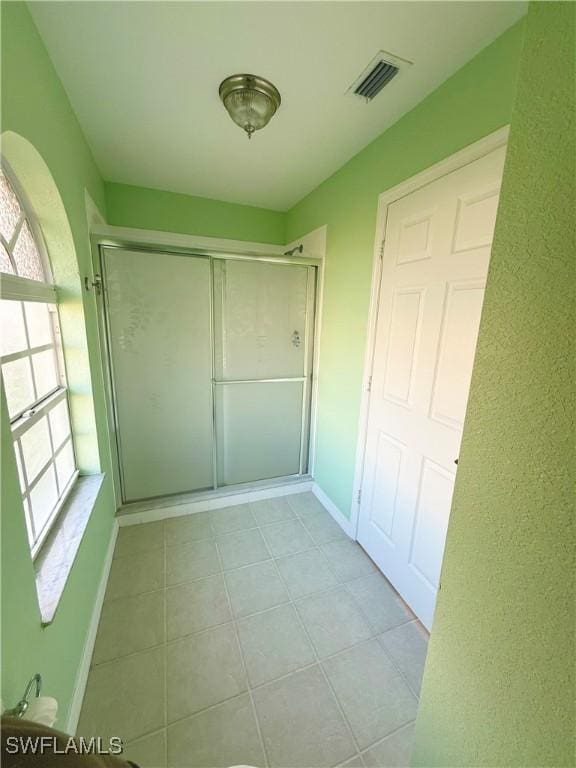 hallway featuring light tile patterned floors, baseboards, and visible vents