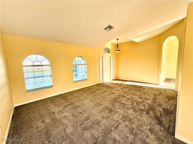 empty room featuring lofted ceiling, carpet floors, visible vents, and baseboards