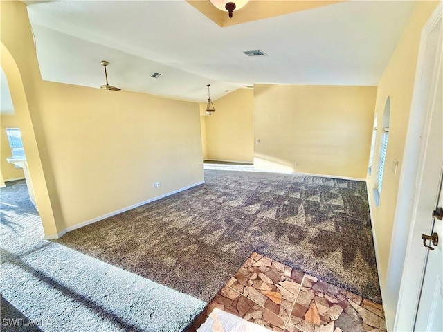 empty room with arched walkways, carpet floors, vaulted ceiling, and visible vents