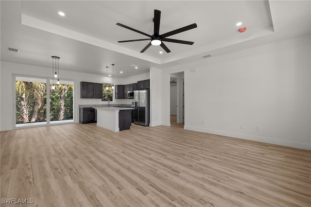 kitchen featuring stainless steel appliances, a tray ceiling, open floor plan, and light countertops