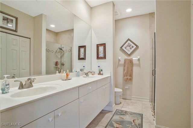 full bathroom with double vanity, a stall shower, toilet, tile patterned flooring, and a sink