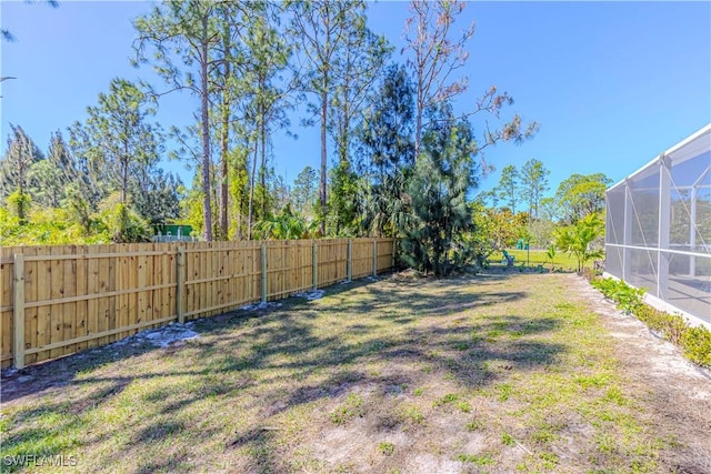 view of yard featuring glass enclosure and a fenced backyard