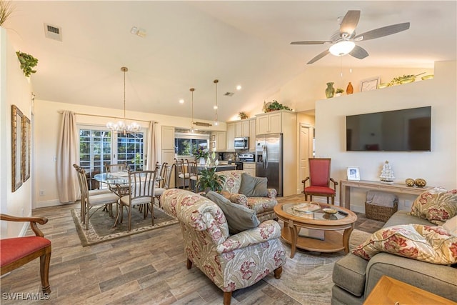 living area featuring visible vents, high vaulted ceiling, ceiling fan with notable chandelier, wood finished floors, and baseboards