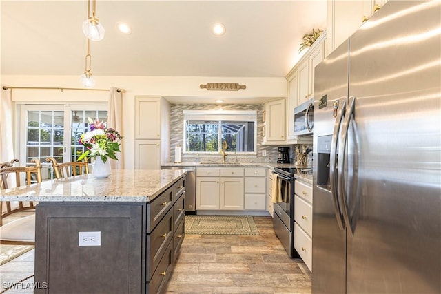 kitchen with a sink, light wood-style flooring, a wealth of natural light, and stainless steel appliances