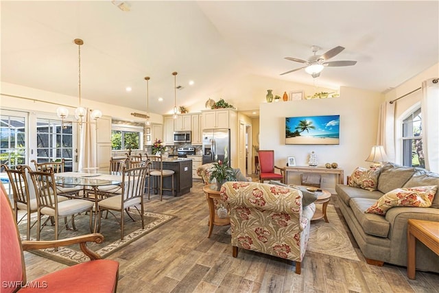 living area featuring ceiling fan with notable chandelier, vaulted ceiling, and wood finished floors