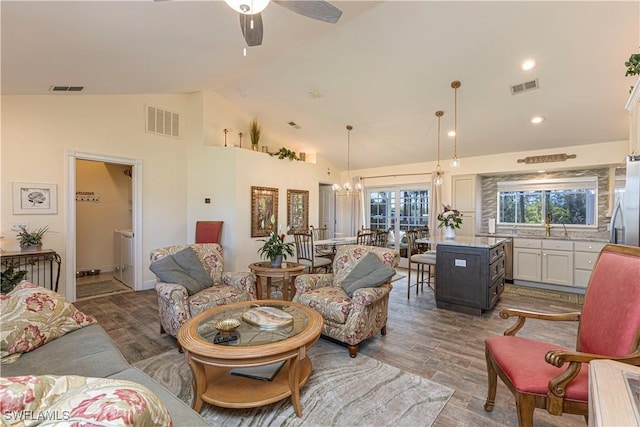 living area with wood finished floors, visible vents, and high vaulted ceiling