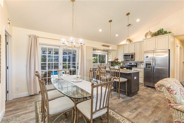 dining room featuring visible vents, a notable chandelier, wood finished floors, baseboards, and lofted ceiling