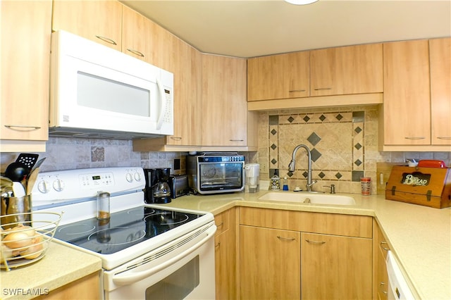 kitchen featuring a sink, decorative backsplash, white appliances, and light countertops