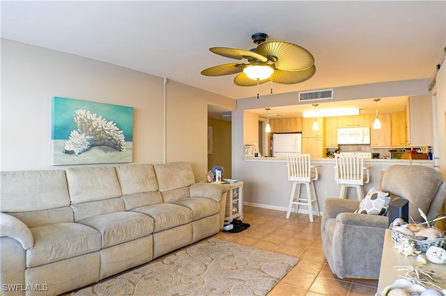 living area featuring light tile patterned floors, visible vents, baseboards, and ceiling fan