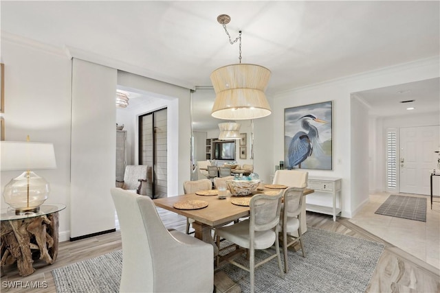 dining area with light wood-style floors, baseboards, and crown molding