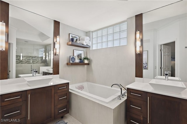 bathroom with two vanities, a shower stall, a bath, and a sink
