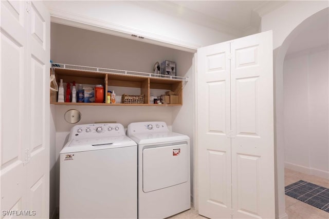 laundry area with light tile patterned floors, washer and clothes dryer, laundry area, and arched walkways