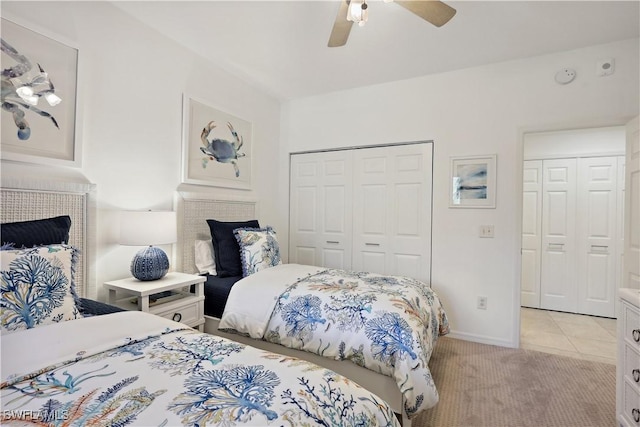 bedroom featuring light tile patterned floors, a closet, light colored carpet, ceiling fan, and baseboards