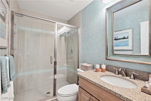 bathroom featuring toilet, a shower stall, and vanity