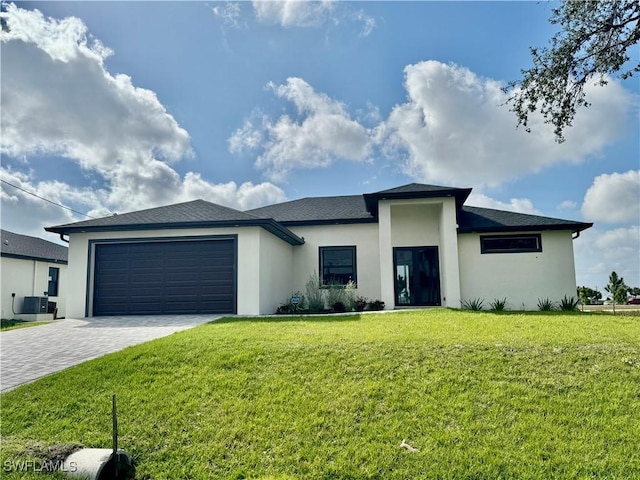 prairie-style house with central AC unit, an attached garage, decorative driveway, a front yard, and stucco siding