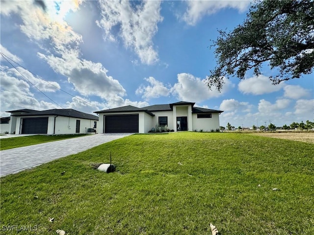 prairie-style home with an attached garage, a front lawn, decorative driveway, and stucco siding