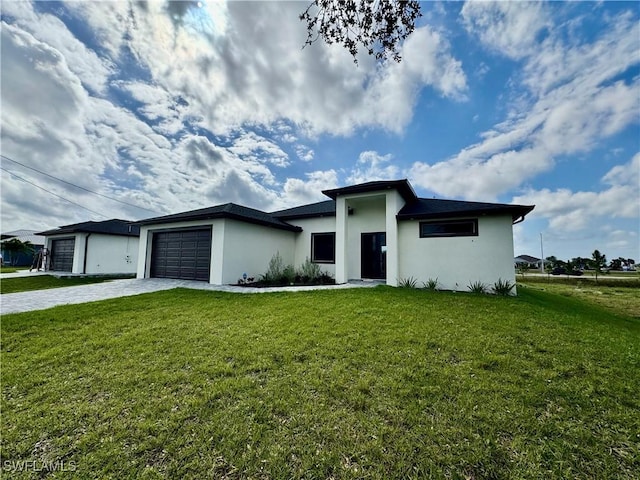 prairie-style home with driveway, stucco siding, an attached garage, and a front yard