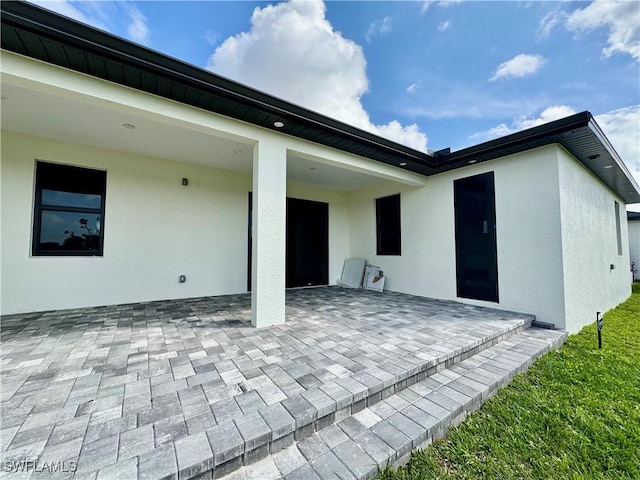 back of property with a patio and stucco siding