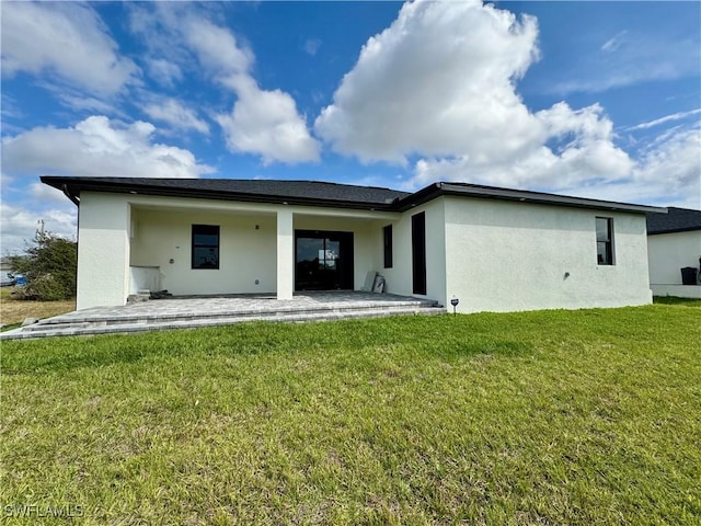 back of property featuring a patio area, a yard, and stucco siding