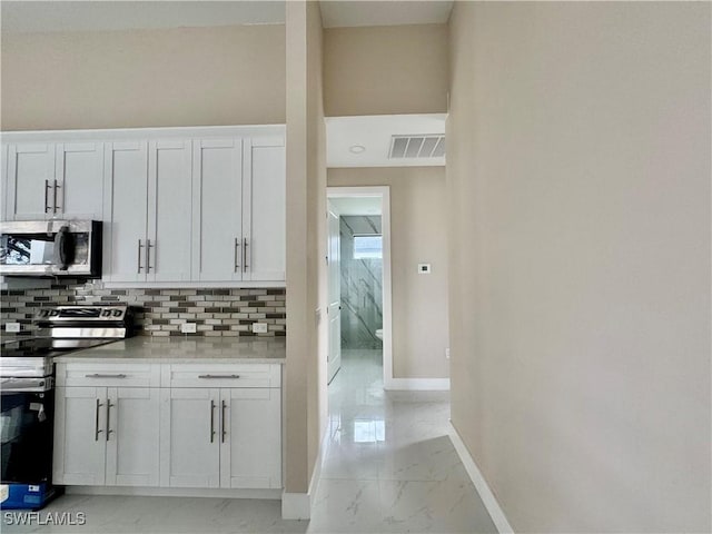 kitchen with marble finish floor, visible vents, backsplash, appliances with stainless steel finishes, and baseboards