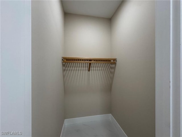 walk in closet featuring marble finish floor