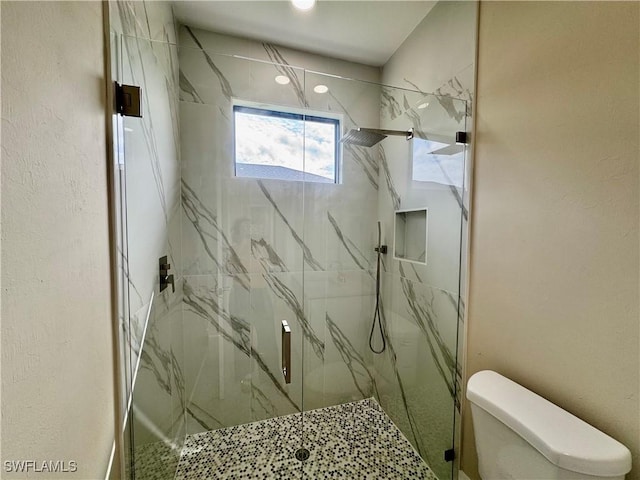 bathroom featuring toilet, a marble finish shower, and a textured wall