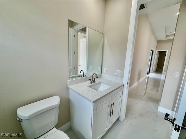 bathroom with marble finish floor, vanity, toilet, and baseboards