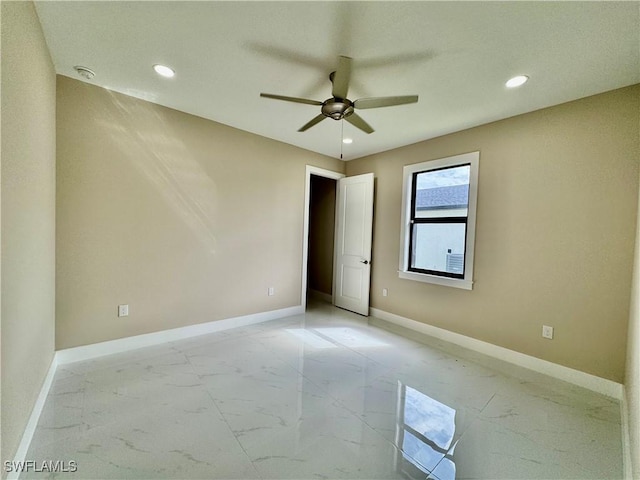 spare room with a ceiling fan, recessed lighting, marble finish floor, and baseboards