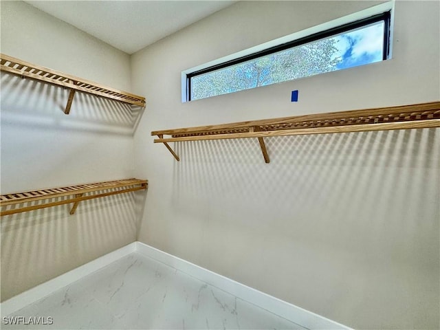 walk in closet featuring marble finish floor