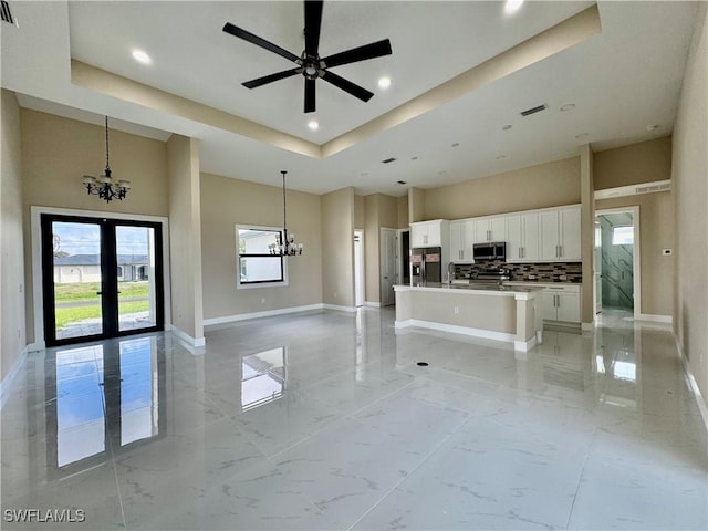 unfurnished living room featuring marble finish floor, a high ceiling, a sink, and baseboards