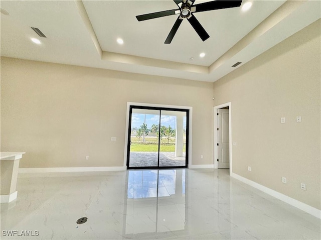 spare room featuring a tray ceiling, marble finish floor, baseboards, and recessed lighting