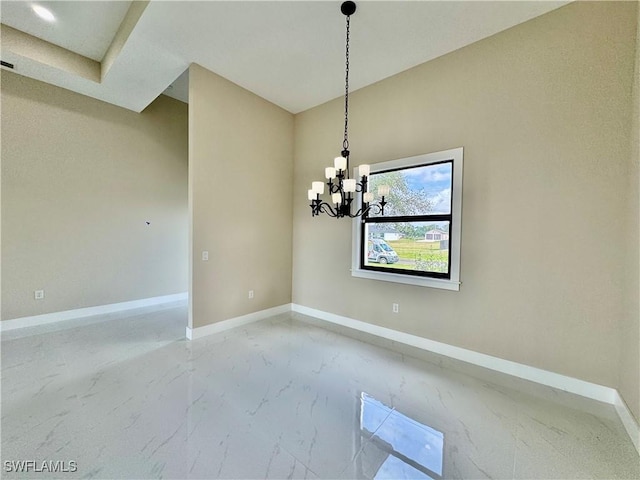 empty room featuring a chandelier, marble finish floor, and baseboards