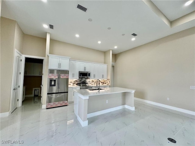 kitchen featuring marble finish floor, stainless steel appliances, backsplash, and a sink