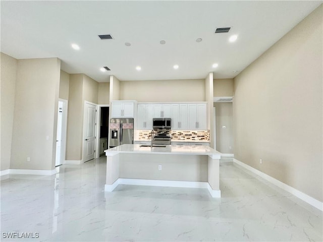 kitchen with a spacious island, visible vents, marble finish floor, appliances with stainless steel finishes, and tasteful backsplash