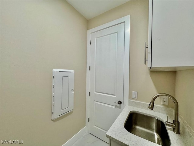 laundry room featuring marble finish floor, a sink, and baseboards