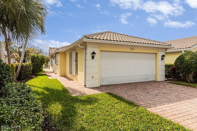 view of side of home with a tiled roof, stucco siding, an attached garage, and decorative driveway