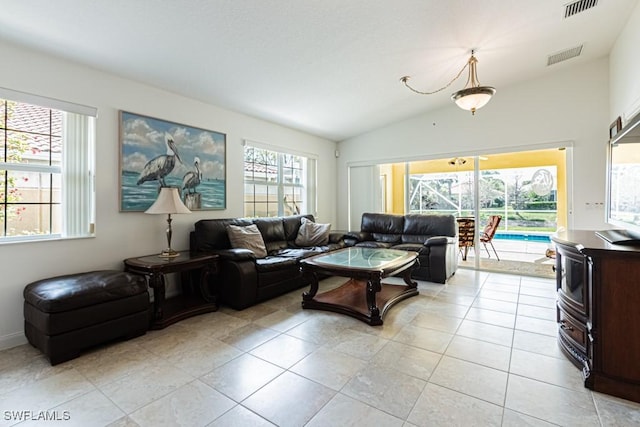 living room featuring light tile patterned floors, visible vents, and vaulted ceiling