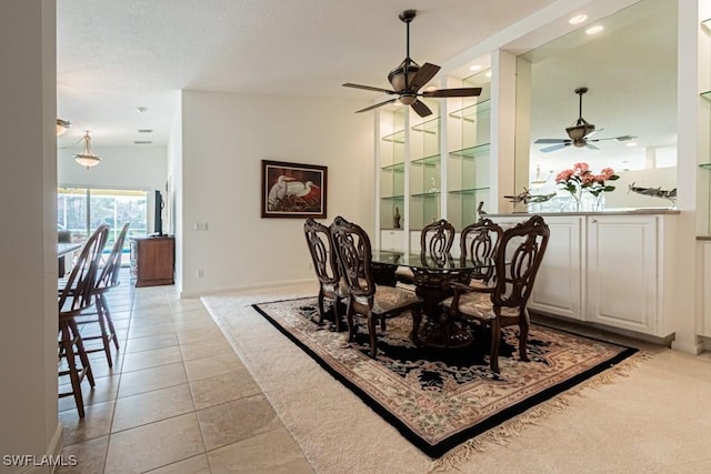 dining space featuring baseboards, ceiling fan, light tile patterned floors, light carpet, and a textured ceiling