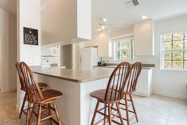 kitchen featuring stove, a kitchen breakfast bar, a peninsula, and white fridge with ice dispenser