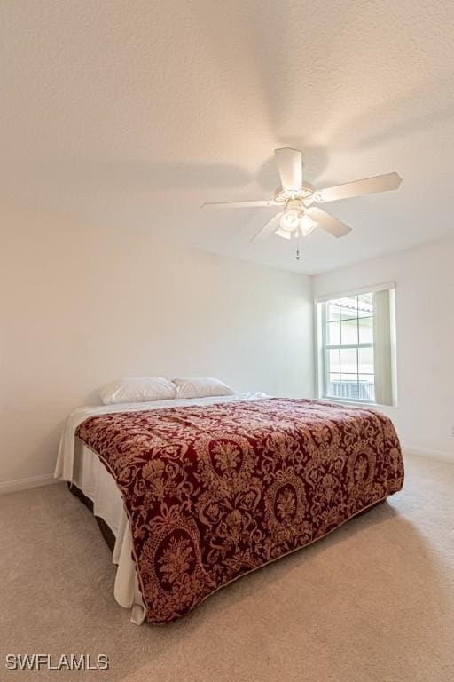 bedroom featuring light colored carpet, baseboards, and ceiling fan