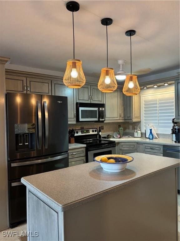 kitchen with decorative light fixtures, a kitchen island, black appliances, and light countertops